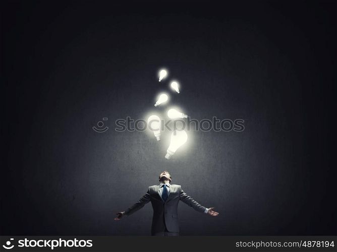 In light of success. Businessman with hands spread apart and light bulbs above