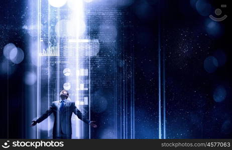 In light of success. Businessman with hands spread apart standing in light coming from above