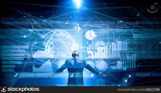 In light of success. Businessman with hands spread apart standing in light coming from above