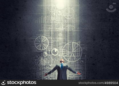 In light of success. Businessman with hands spread apart standing in light coming from above