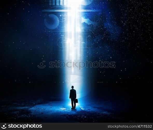 In light of success. Rear view of businessman standing in light going from above