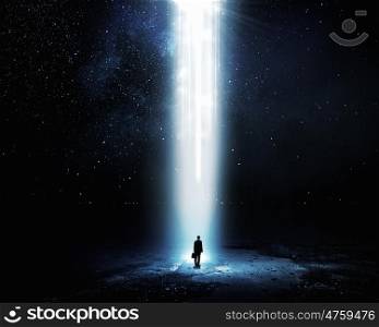 In light of success. Rear view of businessman standing in light going from above