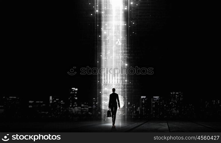 In light of success. Rear view of businesswoman standing in light going from above