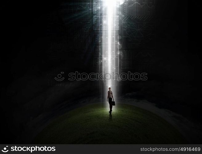In light of success. Rear view of businesswoman standing in light going from above
