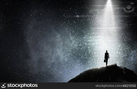 In light of success. Rear view of businesswoman standing in light going from above