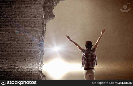 In light of success. Rear view of woman with hands up entering crack in wall