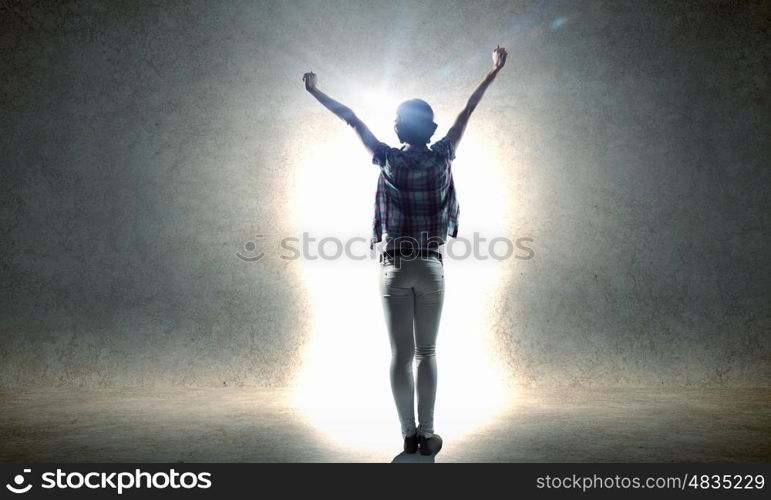 In light of success. Rear view of woman with hands up entering crack in wall