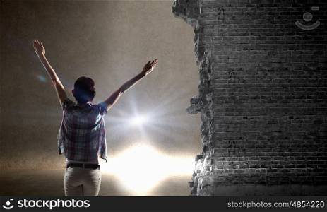 In light of success. Rear view of woman with hands up entering crack in wall