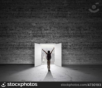 In light of success. Rear view of woman with hands up entering opened door