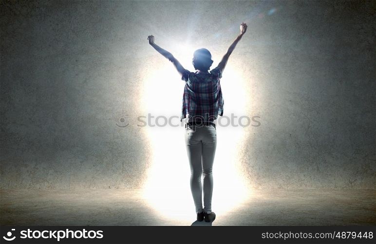 In light of success. Rear view of woman with hands up facing success