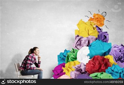 In search of good idea and inspiration. Young woman and heap of paper balls as symbol of creativity