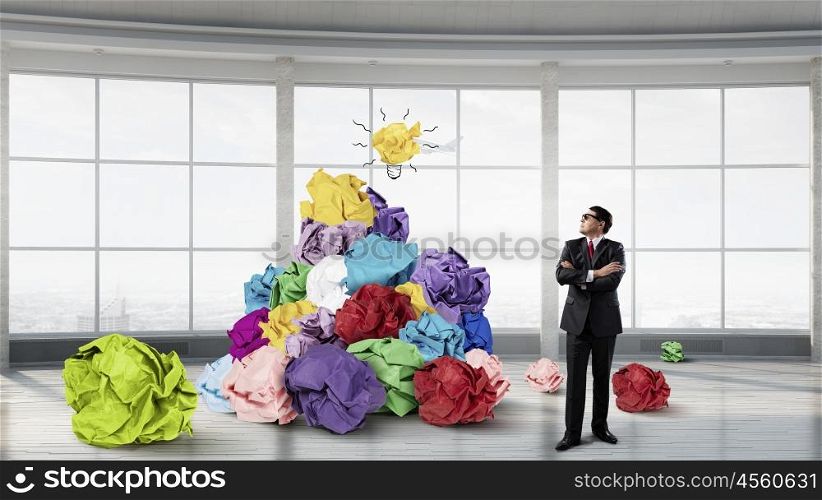 In search of his great idea. Adult businessman in modern interior and heap of paper balls