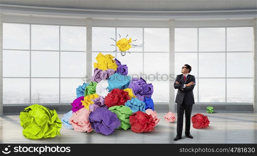 In search of his great idea. Adult businessman in modern interior and heap of paper balls