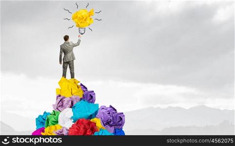 In search of his great idea. Young businessman standing on heap of paper balls