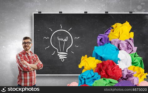 In search of his great idea. Young man at blackboard and paper balls as symbol of creativity