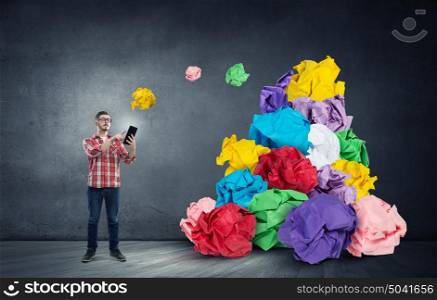 In search of his great idea. Young man in modern interior and paper balls as symbol of creativity