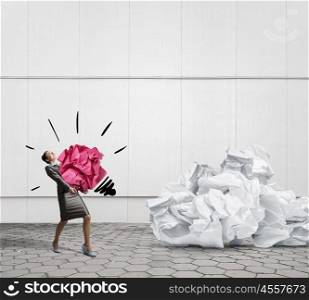 In search of inspiration. Woman carrying with effort big crumpled ball of paper as creativity sign