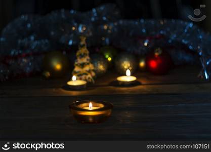 In the decorative stand a small candle burns on the background of New Year's toys and tinsel