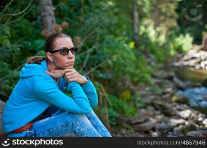 In the forest. Portrait of attractive woman sitting in forest