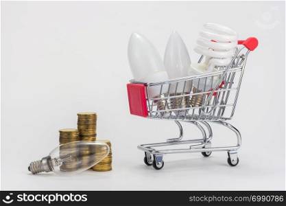In the grocery cart are LED and energy-saving light bulbs, near the incandescent lamp and stacks of coins