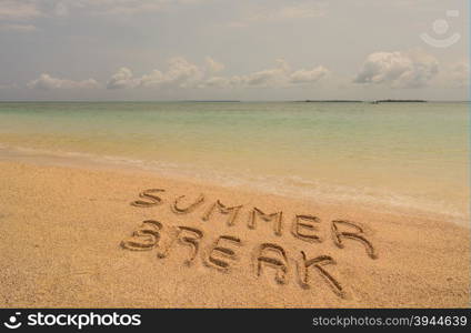 "In the photo a beach in Zanzibar in the afternoon where there is an inscription on the sand "Summer Break"."