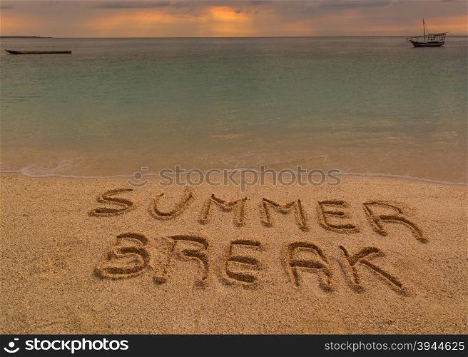 "In the picture a beach at sunset with the words on the sand "Summer break"."