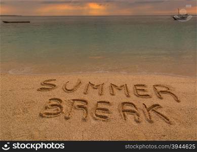 "In the picture a beach at sunset with the words on the sand "Summer break"."