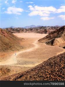 In the picture the Egyptian desert of stones with its mountains of many colors and man walking alone.