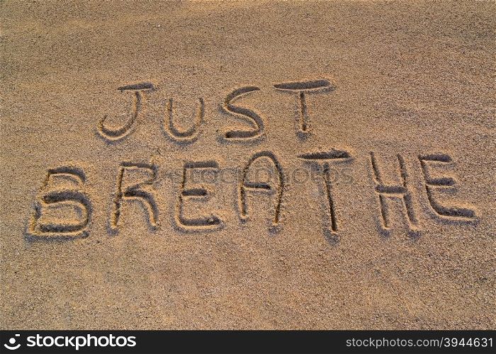 "In the picture the words on the sand "Just breathe"."