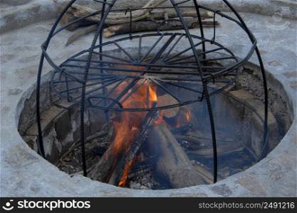 in the pit a construction of metal rods for smoke. metal structure for cooking on fire. metal structure smokehouse
