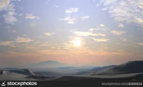 In the vast blue sky small white clouds. Bright sun slowly sets behind the horizon, covered in hot summer haze. Over the hills and lowlands light fog. Sunset colors the landscape in reddish tones.