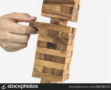 Inclined wooden block tower jenga game with hand, risk concept