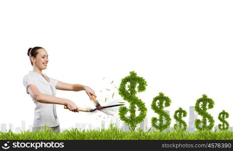 Income concept. Young attractive businesswoman cutting plant in shape of dollar