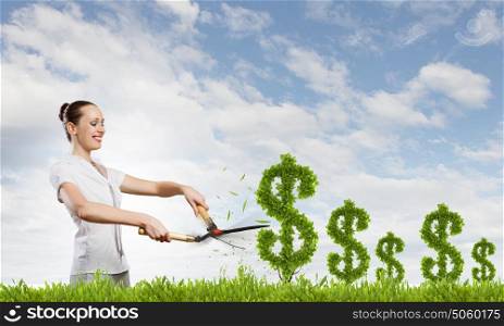 Income concept. Young attractive businesswoman cutting plant in shape of dollar