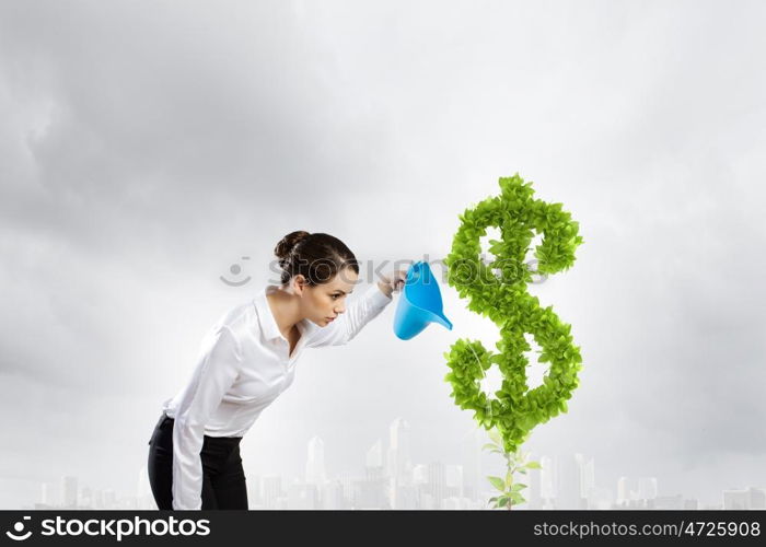 Income concept. Young attractive businesswoman watering plant in pot with can