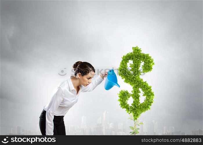 Income concept. Young attractive businesswoman watering plant in pot with can