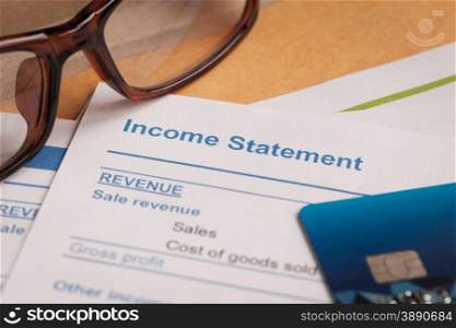 Income statement letter on brown envelope and eyeglass, business concept; document is mock-up