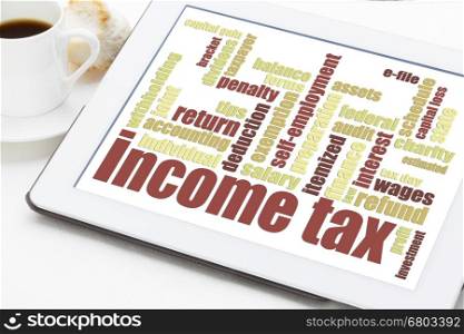 income tax word cloud on a digital tablet with a cup of coffee