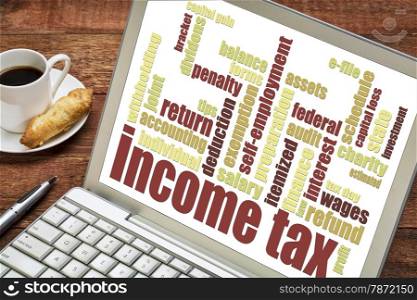 income tax word cloud on a laptop screen with a cup of coffee