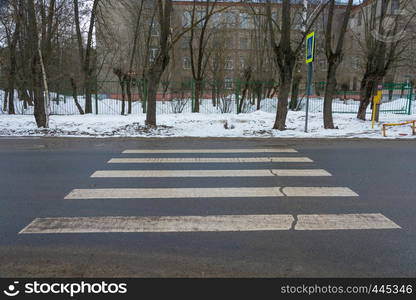 Incorrectly designed pedestrian crossing on an asphalt road, resting on a snow drift.