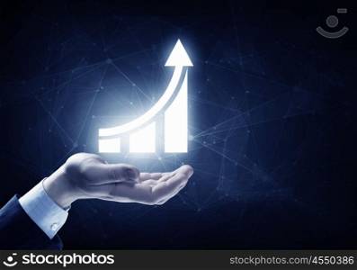Increase your financial income . Businessman hand on dark background holding growing graph