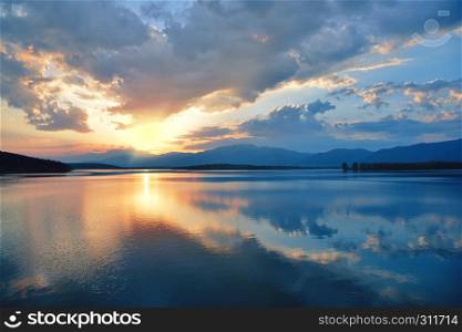 Incredibly beautiful sunset.Sun, blue sky,lake.Sunset or sunrise landscape, panorama of beautiful nature. Sky with amazing colorful clouds. Water reflections.Magic Artistic Wallpaper.Dream, line.Creative Background.