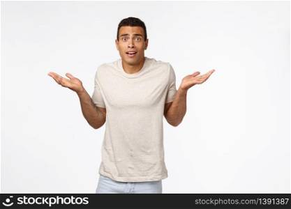 Indecisive handsome hispanic man with short haircut, wear t-shirt, shrugging with arms spread sideways look worried and puzzled, cant figure out what do, dont know, standing confused white background.. Indecisive handsome hispanic man with short haircut, wear t-shirt, shrugging with arms spread sideways look worried and puzzled, cant figure out what do, dont know, standing confused white background