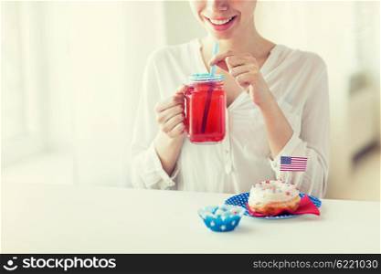 independence day, celebration, patriotism and holidays concept - close up of happy woman eating glazed sweet donut, drinking juice from glass mason jar or mug and celebrating 4th july at home party