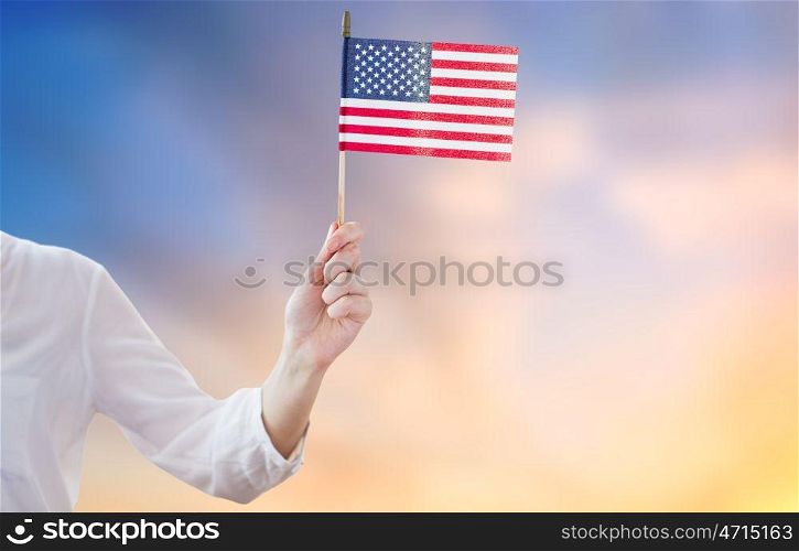 independence day, celebration, patriotism and holidays concept - close up of woman holding american flag in hand at 4th july party over evening sky background. close up of woman holding american flag in hand. close up of woman holding american flag in hand