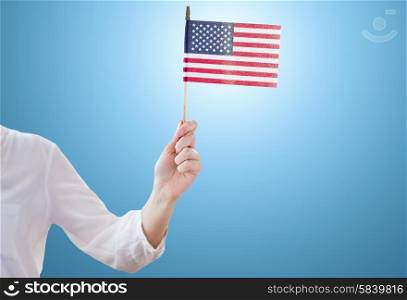 independence day, celebration, patriotism and holidays concept - close up of woman holding american flag in hand at 4th july party over blue background