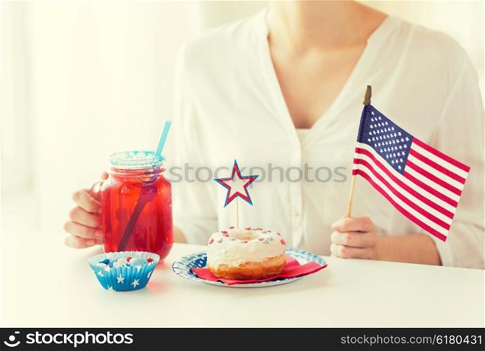 independence day, celebration, patriotism and holidays concept - close up of woman eating glazed sweet donut, drinking juice from big glass mason jar or mug and celebrating 4th july at home party