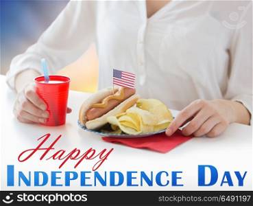independence day, patriotism and holidays concept - close up of woman eating hot dog with american flag decoration and potato chips, drinking juice and celebrating 4th july. woman celebrating american independence day. woman celebrating american independence day