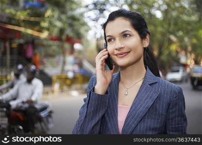 India, business woman using mobile phone on street