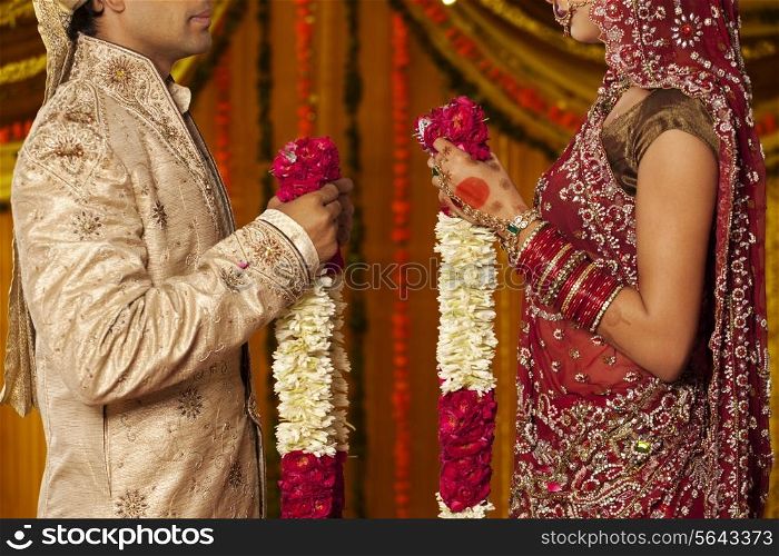 Indian bride and groom holding garlands